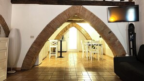 An attic room with a vaulted ceiling, a TV mounted on the wall, and a dining area with chairs and a table. - The arches in the heart of Siena (Siena)