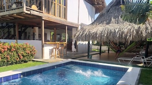 Una piscina con cubierta de madera y techo de paja.