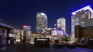 Una terrazza sul tetto con posti a sedere all'aperto, vista su edifici illuminati e una bandiera.
