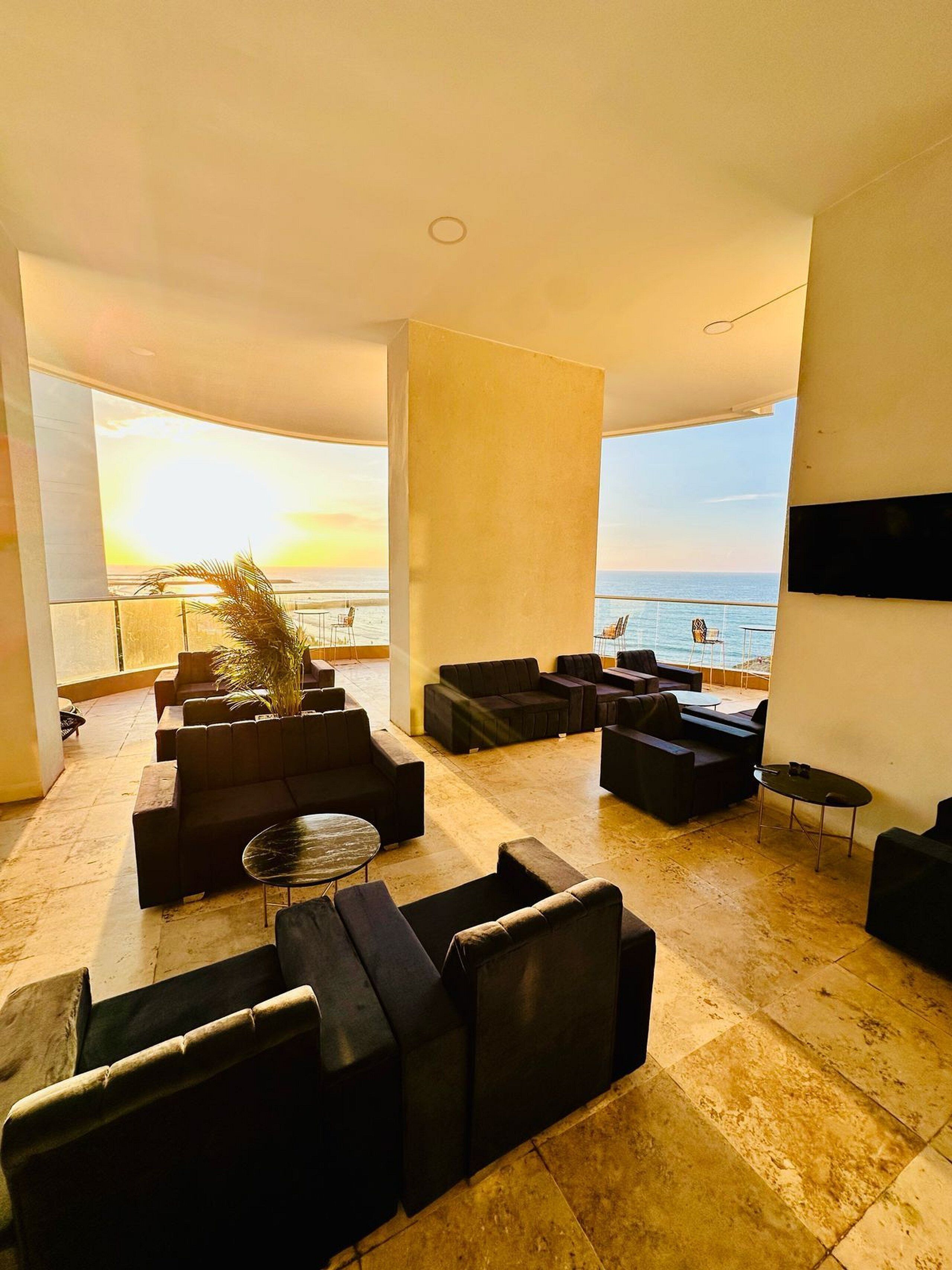 A spacious lounge area with multiple seating options and a view of the ocean.