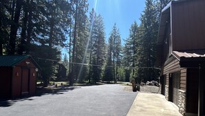 A parking area with a building on the right and a small structure on the left. - Cozy Pines Cabin (Ronald)