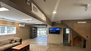 A spacious living area with a sofa, coffee table, and a flat-screen TV mounted on the wall. - Cozy Pines Cabin (Ronald)