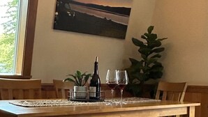 A dining area with a wooden table, benches, a chandelier, a painting, and a potted plant. - Cozy Pines Cabin (Ronald)