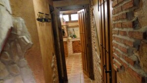 A narrow hallway with tiled flooring, brick walls, and wooden doors. - Casa Ribera del Pisuerga - Piscina Privada a 10 Minutos del Centro de Valladolid (Arroyo de la Encomienda)
