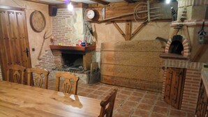 A rustic dining area with a wooden table and chairs, a brick fireplace, and a brick oven. - Casa Ribera del Pisuerga - Piscina Privada a 10 Minutos del Centro de Valladolid (Arroyo de la Encomienda)