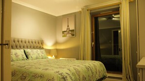 A hotel room with a bed, a nightstand, a lamp, a door leading to a balcony, and a picture of the Eiffel Tower on the wall. - Lux 2 Bed in Canary Wharf Close to Excel & O2 (London)
