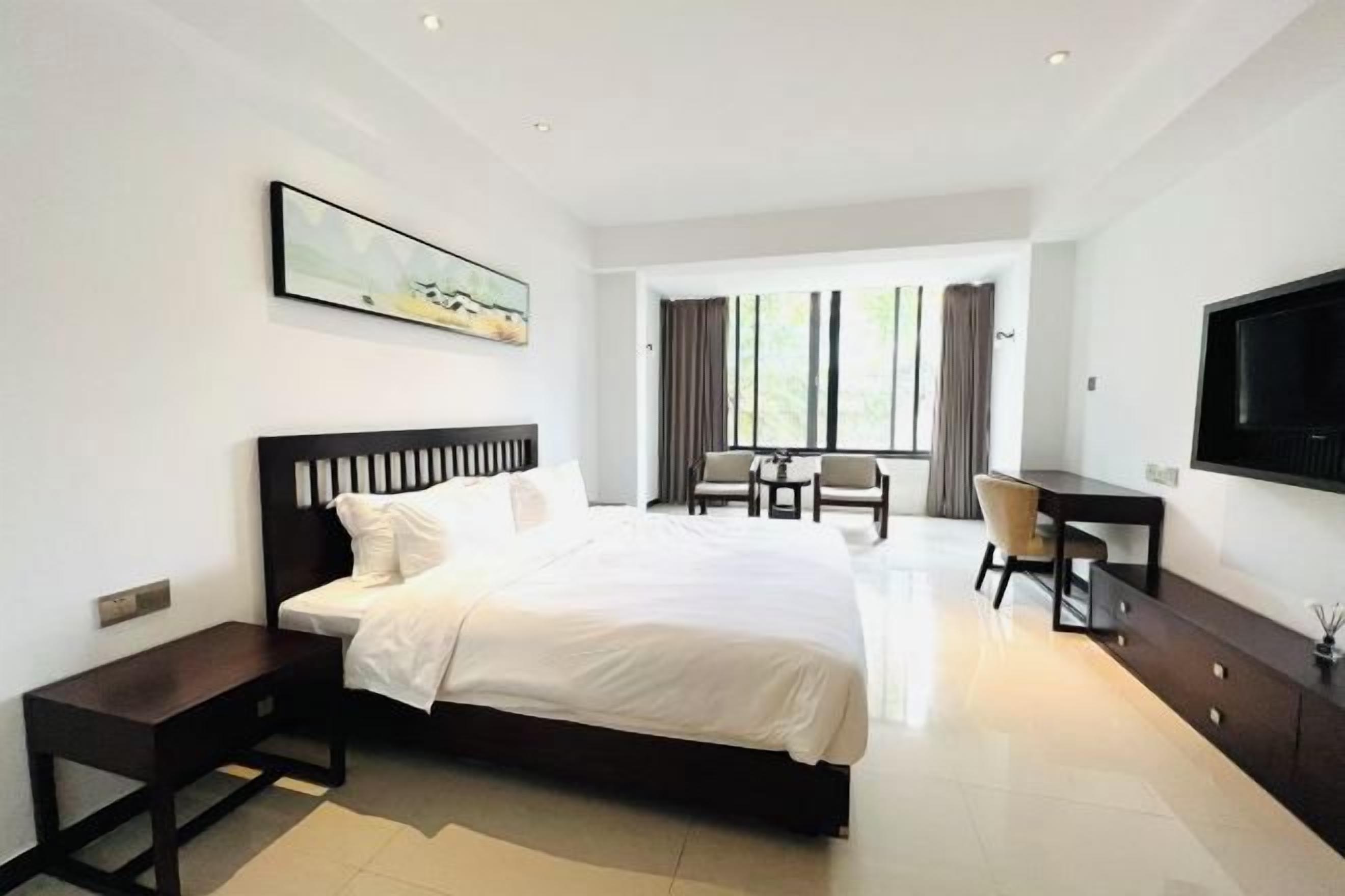 A modern hotel room with a large bed, a desk, and a TV.