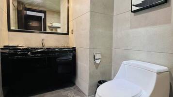 A bathroom with a black marble sink, a white toilet, and a large mirror.