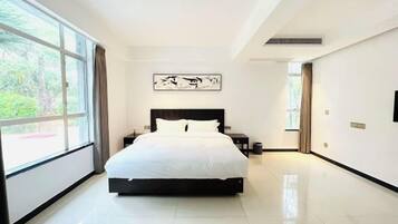 A modern bedroom with a large bed, a nightstand, a wall-mounted artwork, and a window with curtains.