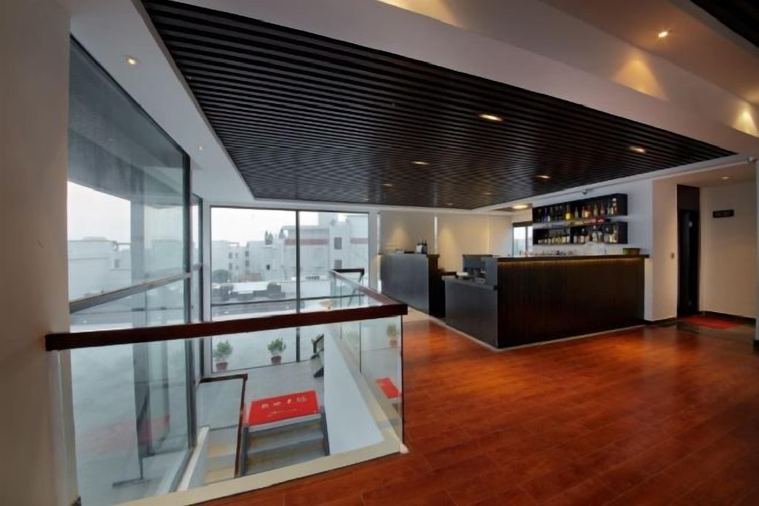 A modern interior with a reception desk, a glass railing, and a view of the city.
