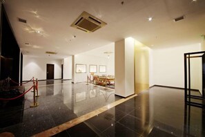 A spacious hotel lobby with a polished floor, a reception desk, and framed artwork on the walls. - Eden Hotel (Shantou)