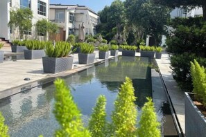 A pool area with potted plants and a building in the background. - Eden Hotel (Shantou)