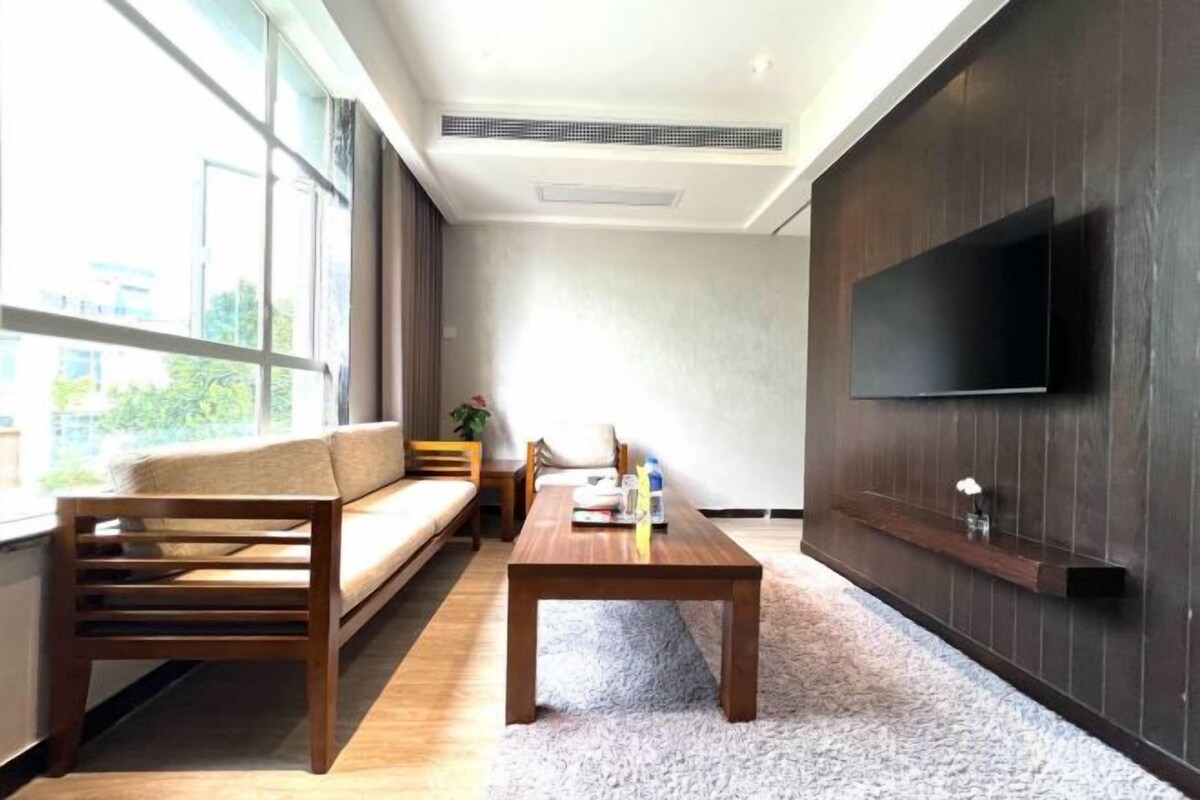 Een moderne woonkamer met een bank, een salontafel en een aan de muur bevestigde televisie.