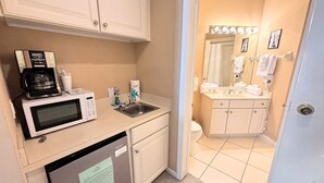 A compact kitchenette with a microwave, coffee maker, and sink.