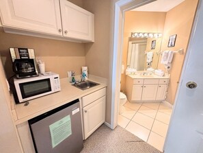 A compact kitchenette with a microwave, coffee maker, and sink.