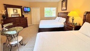 A bedroom with two beds, a desk, a chair, a television, a ceiling fan, and a window.