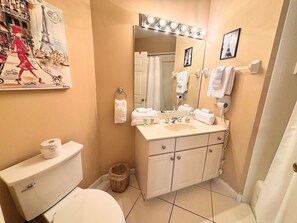 A bathroom with a toilet, sink, mirror, and a painting of a cityscape.