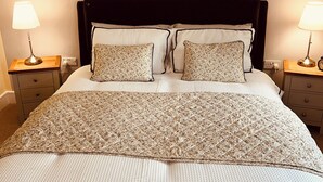 A bedroom with a large bed, two nightstands, two lamps, and two paintings on the wall. - Claverley Hideaway Apartment Bridgnorth (Wolverhampton)