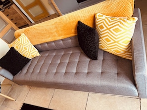 A grey sofa with a textured backrest and a yellow throw blanket. - Claverley Hideaway Apartment Bridgnorth (Wolverhampton)