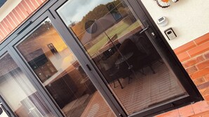 A sliding glass door with a mesh screen, a butterfly wall decoration, and a security camera on the wall. - Claverley Hideaway Apartment Bridgnorth (Wolverhampton)