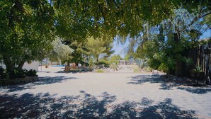 A spacious outdoor area with a variety of trees and plants, a fenced play area, and a clear sky. - Accommodation LA GUITARRA ANDALUZA  (Loja)