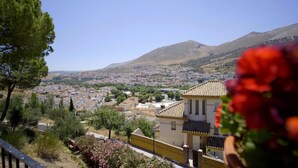 A town with a prominent yellow building, surrounded by greenery and mountains in the background. - Accommodation LA GUITARRA ANDALUZA  (Loja)