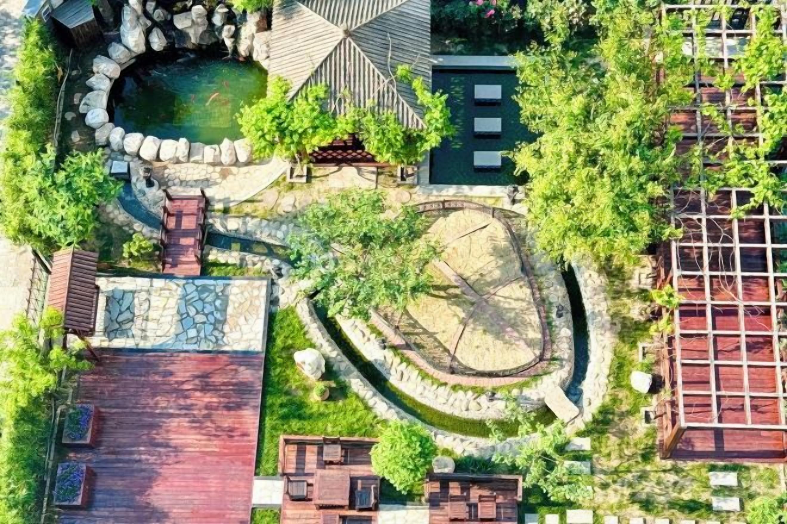 Luchtbeeld van een pand met een zwembad, een ronde tuin en een gebouw met een rood dak.