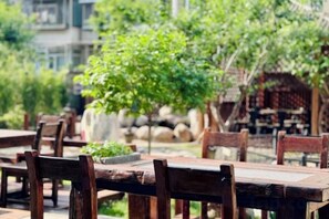 Outdoor wooden tables and chairs in a garden setting with stone walls and greenery. - Wanshang Ruyi Hotel (Beijing Lugu East Street) (Beijing)