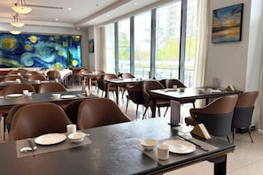 A dining area with tables set for service, large windows, and a painting on the wall. - Wanshang Ruyi Hotel (Beijing Lugu East Street) (Beijing)