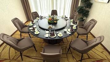 Un salón de conferencias con una mesa redonda, seis sillas y una planta en maceta.