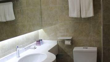 Un baño con lavamanos, inodoro y toallero.
