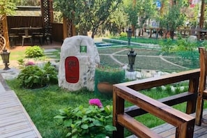 A garden with a stone feature, a wooden deck, and a fountain. - Wanshang Ruyi Hotel (Beijing Lugu East Street) (Beijing)