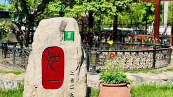Un monumento de piedra con un símbolo rojo, un cartel verde y una planta en maceta a su lado.