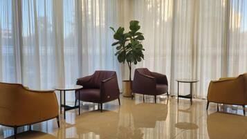 A room with a large window, a potted plant, and four chairs arranged around a small table.