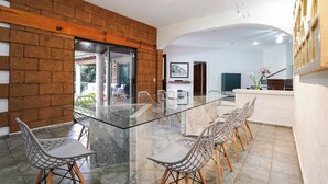 Un comedor moderno con una mesa y sillas de vidrio, paredes de ladrillo y vistas al exterior.
