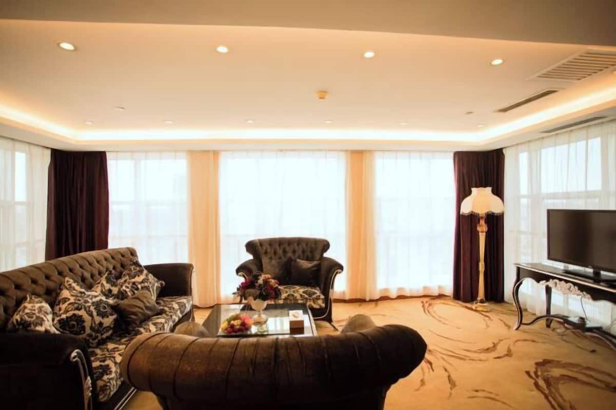Moderni hotellihuone, jossa on suuri ikkuna, sohva, nojatuoli, sohvapöytä ja televisio.