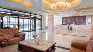 A lobby with a reception desk, a chandelier, and leather sofas. - Vienna International Hotel (Tongliao Kerqin) (Tongliao)