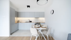 Una cucina moderna con pensili bianchi, un tavolo da pranzo per due persone e una lampada a sospensione sopra.