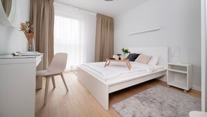 Una camera da letto moderna con un letto, un comodino, una sedia, una scrivania e un piccolo armadietto bianco.