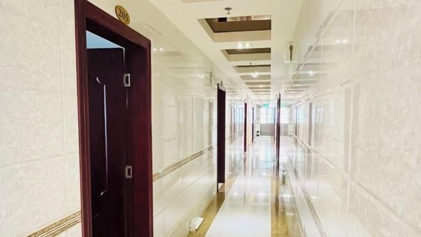 A long, well-lit corridor with marble walls and a polished floor, leading to a door marked with the number 205. - Taiyuan Hostel (Dabu)