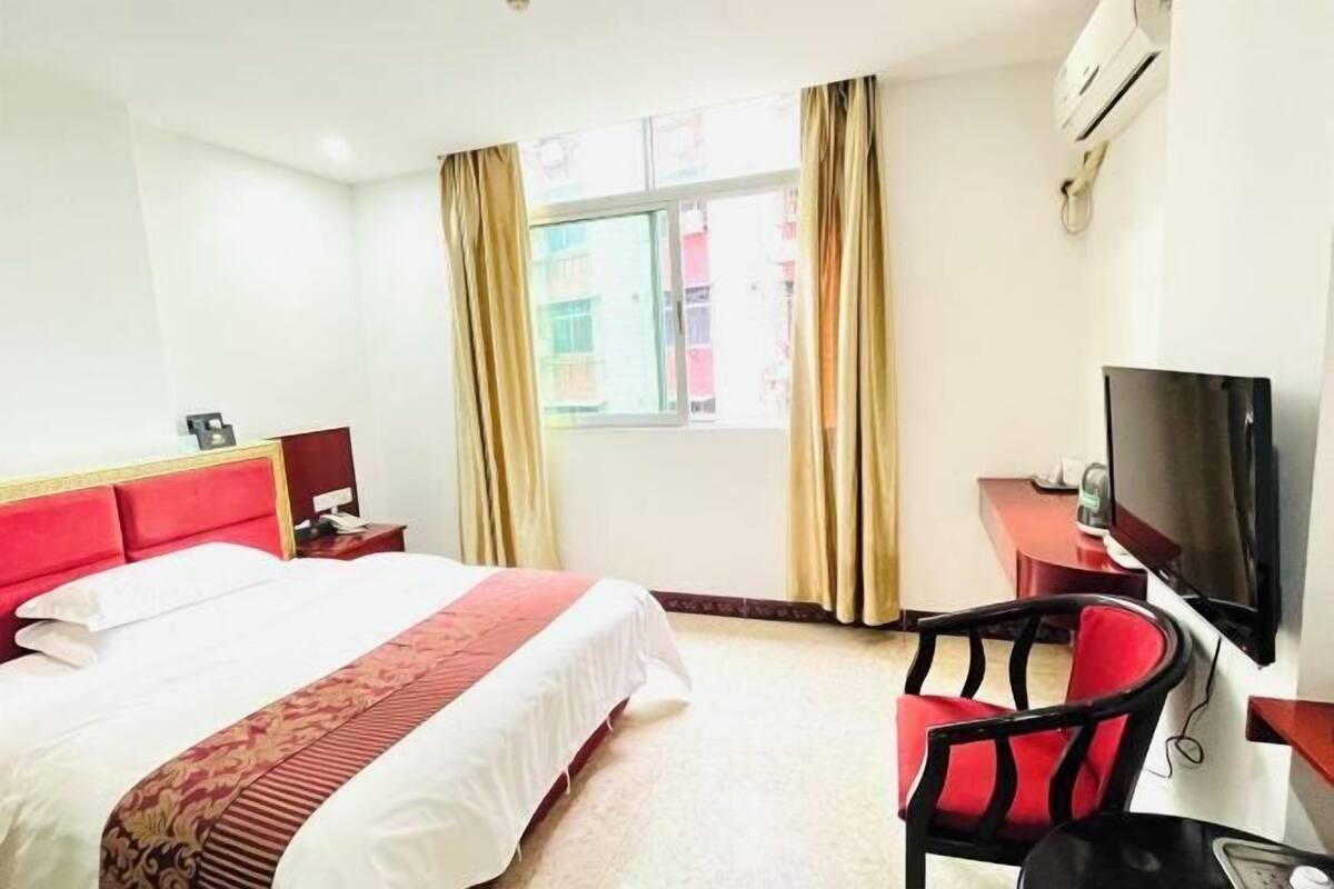 A hotel room with a bed, a TV, a desk, and a chair.