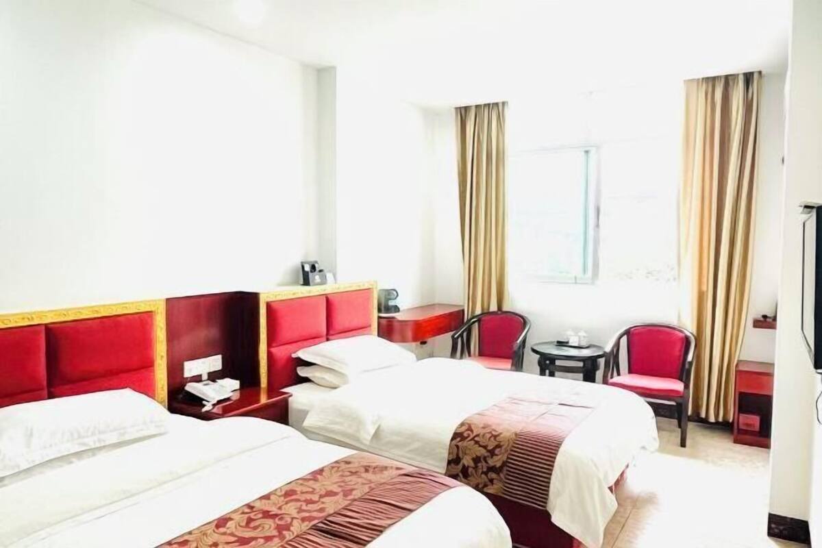 A hotel room with two beds, a desk, a chair, and a window with curtains.