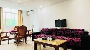 A living room with a sofa, a coffee table, and a TV mounted on the wall. - Taiyuan Hostel (Dabu)