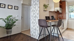 Moderni keittiö, jossa on ruokailutila. Keittiössä on puinen työtaso, baarituolit ja riippuvalaisin.
