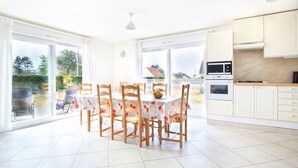 Una cocina luminosa con armarios blancos, un microondas y un comedor con una mesa y sillas.