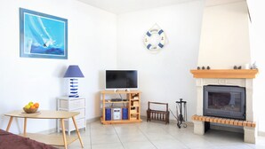Una sala de estar con televisión de pantalla plana, chimenea, un cuadro y un letrero de bienvenida.