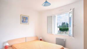 A bedroom with a bed, a window, a radiator, and a picture on the wall. - Les PerceNeige - Maison 85 m² à Port-Bail-Sur-Mer (Portbail)