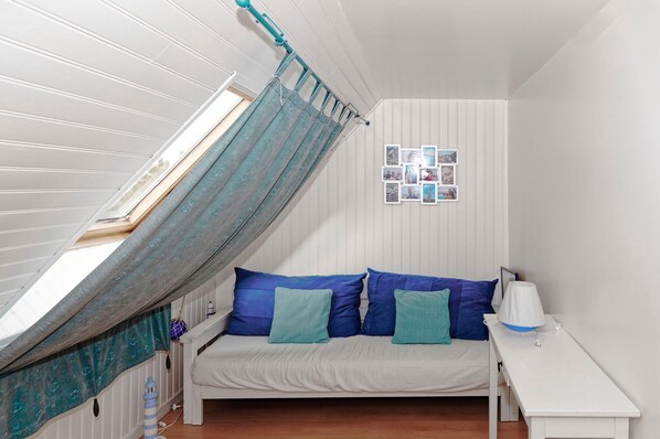 A small, cozy room with a bed, a nightstand, and a window with a curtain.