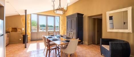 A dining area with a table set for four, a dark-colored cabinet, and a wicker chair.