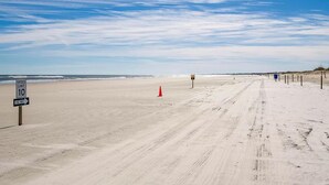 A sandy beach with a speed limit sign, a one-way sign, and a lifeguard flag. - Modern St Augustine Beach Condo with Pool and Private Garage, Steps to Ocean. (St. Augustine)